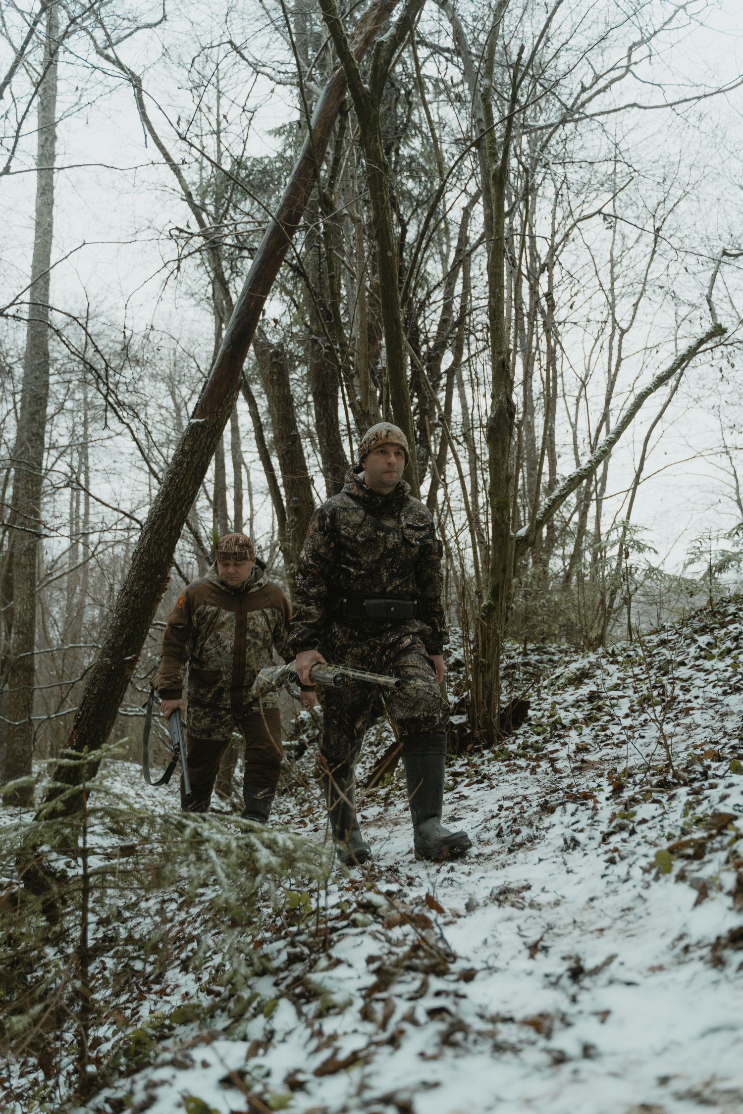 Two hunters moving through a forest